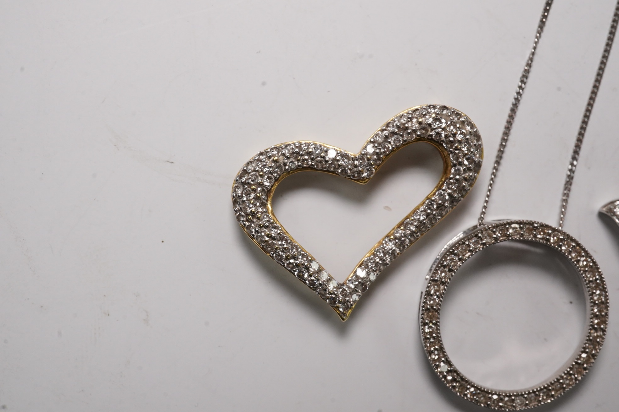 A modern 18k and diamond cluster set open work heart pendant, 25mm, a 9ct white gold and diamond chip set circular pendant necklace and o 9ct and Tahitian cultured pearl set pendant. Condition - fair to good